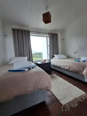 a bedroom with two beds and a large window at Alibi at the Sea in Bettyʼs Bay