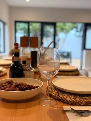 a table with a glass of wine and a bowl of food at Stunning Home in Hermanus Town Centre in Hermanus