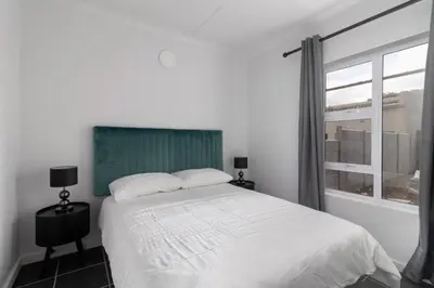 a bedroom with a white bed and a window at 4 Essex Street Apartment in Cape Town