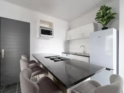 a kitchen with a table and chairs and a refrigerator at 4 Essex Street Apartment in Cape Town