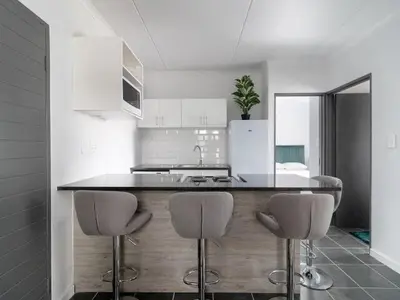 a kitchen with a counter with three stools in it at 4 Essex Street Apartment in Cape Town