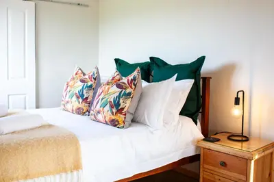 a bedroom with a white bed with green pillows at Kleinhuisie in Hermon