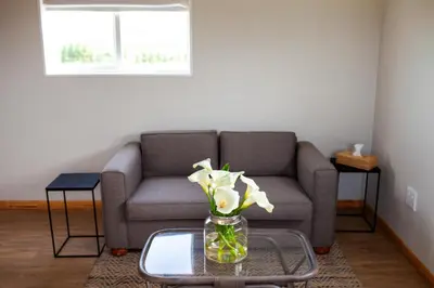 a living room with a couch and a vase with flowers at Kleinhuisie in Hermon