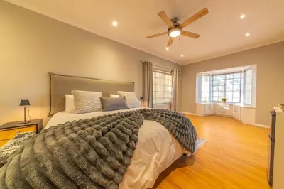 a bedroom with a large bed and a ceiling fan at LEO Sky Guest House in Simondium