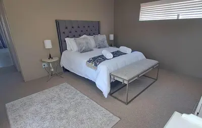 a bedroom with a large white bed and a chair at Close to the sea and sea path in Hermanus