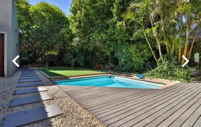 a backyard with a swimming pool and a wooden deck at Close to the sea and sea path in Hermanus