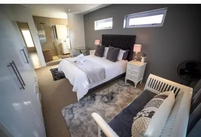 a bedroom with a large white bed and a mirror at Close to the sea and sea path in Hermanus