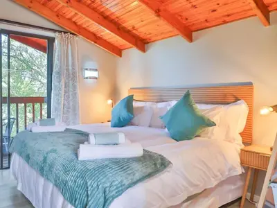 a bedroom with a large white bed with blue pillows at The Fisherman's LAB Cabin in Hermanus