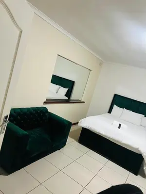 a bedroom with a bed and a mirror and a chair at AFRICAN HAVEN GUEST HOUSE BnB GOODWOOD in Cape Town