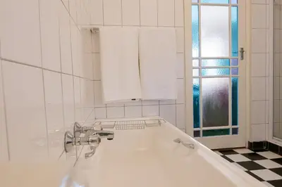 a white bath tub in a bathroom with a window at Wholeness Accommodation in Hermanus
