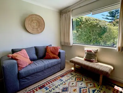 a living room with a blue couch and a window at Wholeness Accommodation in Hermanus