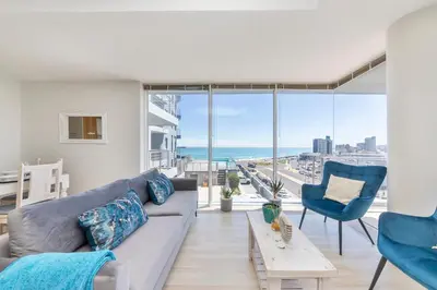 a living room with a couch and chairs and the ocean at Horizon Bay 206 by HMH in Cape Town