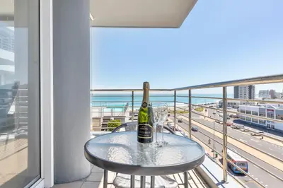 a table with a bottle of wine on a balcony at Horizon Bay 206 by HMH in Cape Town