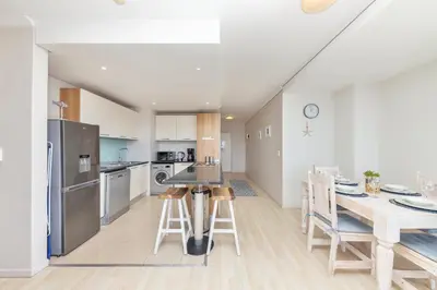 a kitchen and dining room with a table and chairs at Horizon Bay 206 by HMH in Cape Town