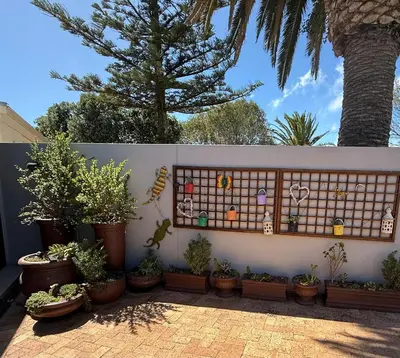 a fence with potted plants and a wall with a lot of plants at Strand cosy 2 bedroom house in Strand