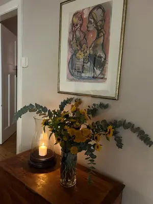 a vase with a candle and flowers on a table at Dottie's charming cottage two bedroom apartment and workspace in Paarl