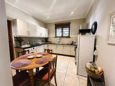a kitchen with a wooden table and a refrigerator at Dottie's charming cottage two bedroom apartment and workspace in Paarl