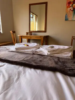 a bed with white sheets and a mirror and a table at Dottie's charming cottage two bedroom apartment and workspace in Paarl