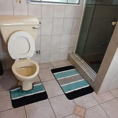 a bathroom with a toilet and a shower and mats at Tripple S in Bellville