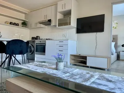 a kitchen with white cabinets and a glass table at 18 On 40 North in Cape Town