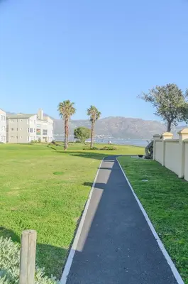 a walkway in a park next to a grass field at Charming Self-catering Apartment in Gordonʼs Bay