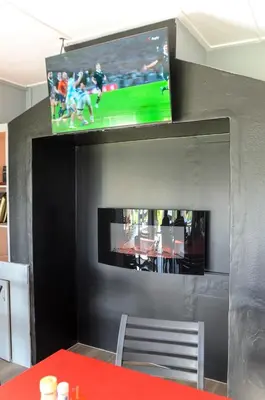 a flat screen tv on a wall with a table with a table sidx sidx at Charming Self-catering Apartment in Gordonʼs Bay