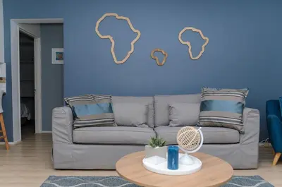 a living room with a couch and a blue wall at Charming Self-catering Apartment in Gordonʼs Bay