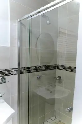a shower with a glass door in a bathroom at Charming Self-catering Apartment in Gordonʼs Bay