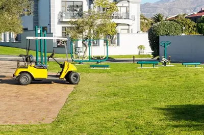 a playground in a park with a yellow vehicle in the grass at Charming Self-catering Apartment in Gordonʼs Bay