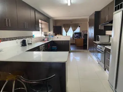 a kitchen with a white counter top and brown cabinets at Ludiz guest house in Parow