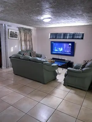 a living room with two couches and a flat screen tv at Ludiz guest house in Parow