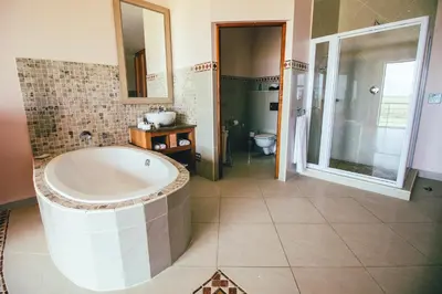 a large bathroom with a tub and a toilet at Castellon Boutique Hotel in Table View