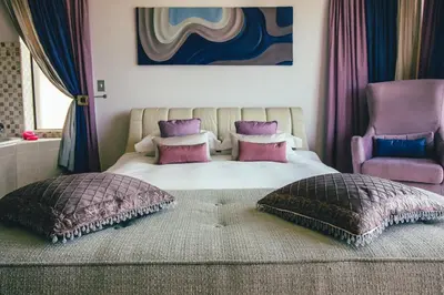 a bedroom with a bed with pillows and a chair at Castellon Boutique Hotel in Table View