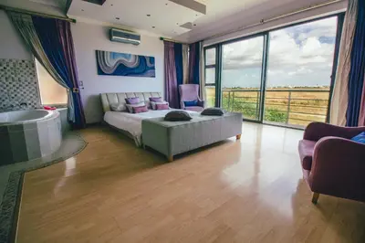 a bedroom with a bed and a tub and a large window at Castellon Boutique Hotel in Table View