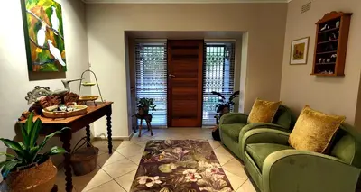 a living room with two green couches and a table at Tuinvrede Guesthouse in Welgemoed
