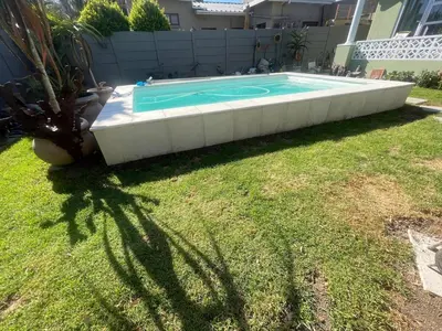 a swimming pool in a yard next to a house at The Grey Hound in Strand