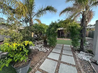 a garden with palm trees and a stone walkway at Suite Dreams Gorgeous Garden Holiday Home in Panorama