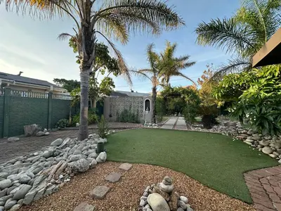 a garden with a lawn and palm trees at Suite Dreams Garden Dream Cottage in Panorama