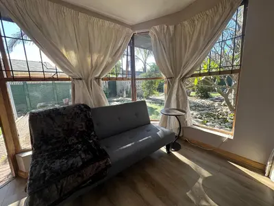 a couch sitting in a room with large windows at Suite Dreams Garden Dream Cottage in Panorama