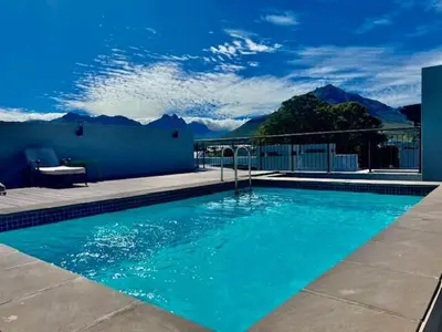 a blue swimming pool with mountains in the background at 34 On The Den in Stellenbosch