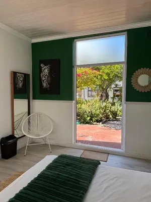 a bedroom with a large window and a green wall at Jacana Lodge Zeekoevlei in Lotus River
