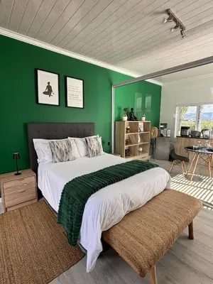 a bedroom with a large bed with a green wall at Jacana Lodge Zeekoevlei in Lotus River
