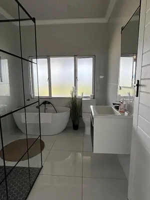 a bathroom with a tub and a sink and two windows at Jacana Lodge Zeekoevlei in Lotus River
