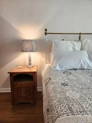 a bed with a table with a lamp on it at Cosy en-suite room Stellenbosch in Stellenbosch
