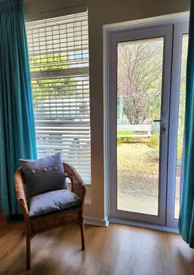 a wicker chair sitting in front of a glass door at Cosy en-suite room Stellenbosch in Stellenbosch