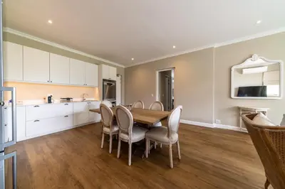 a kitchen and dining room with a wooden table and chairs at 68 LErmitage Elegant Mountain Apartment in Franschhoek