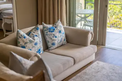 a couch with blue and white pillows in a living room at 68 LErmitage Elegant Mountain Apartment in Franschhoek
