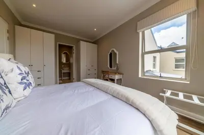 a bedroom with a large white bed and a window at 68 LErmitage Elegant Mountain Apartment in Franschhoek