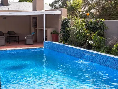 a blue swimming pool in front of a house at Julinas Guesthouse in Panorama