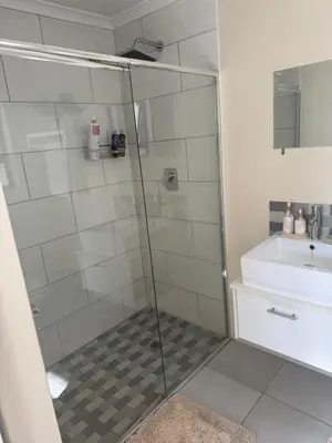 a shower with a glass door next to a sink at Little Haven in Kenridge
